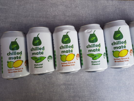 5 cans of Chilled Mate Yerba Energy Drinks laid flat in a diagonal line across a light slate grey background