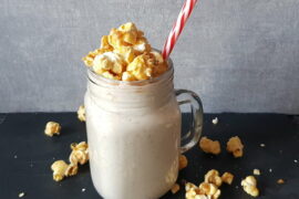 Pecan Pie smoothie in a mason jar mug topped with popcorn and a red and white striped straw