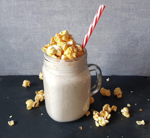 Pecan Pie smoothie in a mason jar mug topped with popcorn and a red and white striped straw