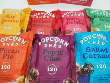7 packets of Popcorn Shed gourmet popcorn laid out on a white background ready for review