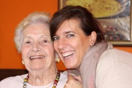 An older mother and her daughter smiling and hugging