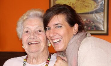 An older mother and her daughter smiling and hugging
