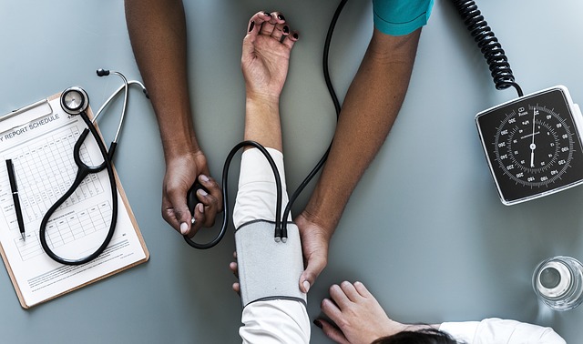 aerial photo of doctors arms taking the blood pressure of a patient