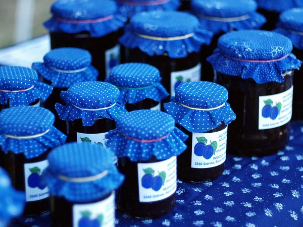 rows of organic plum jam in jars with purple cloth lids and hand printed labels