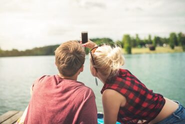 Couple sat in a boat on a lake taking a selfie