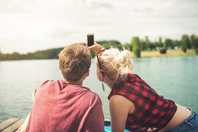 Couple sat in a boat on a lake taking a selfie