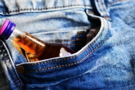 small bottle of brandy poking out of the pocket of a pair of blue jeans suggesting the person had addiction issues