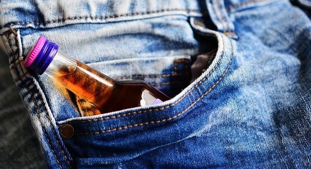 small bottle of brandy poking out of the pocket of a pair of blue jeans suggesting the person had addiction issues