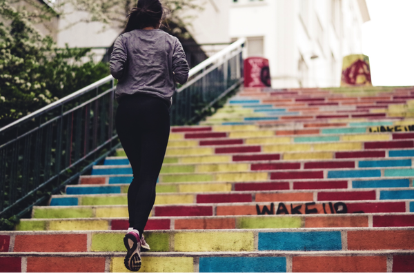 Female runner running up coloured steps to get to the street above and carry on her morning run
