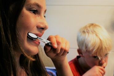 close up of two young children brushing their teeth