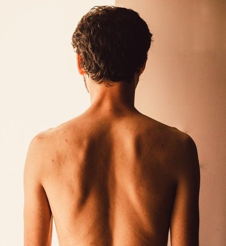 Back of a man from mid chest up. He doesn't have a top on.