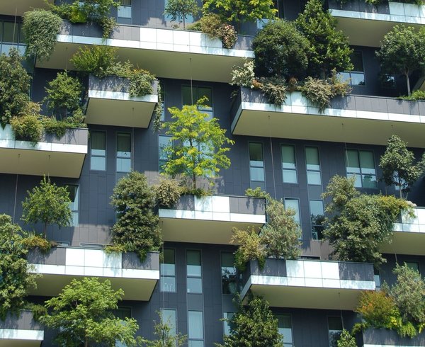 Exterior of a tall building with balconies that are filled with greenery and trees