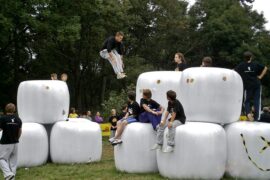 teenagers doing parkour across giant white cubes in a park as an alterantive to playing video games