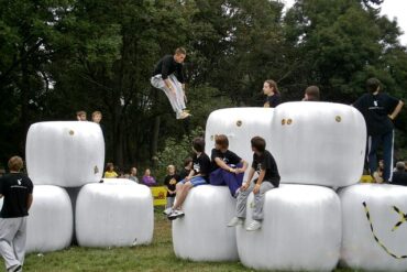teenagers doing parkour across giant white cubes in a park as an alterantive to playing video games