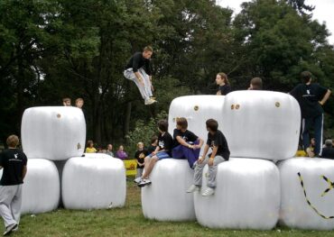teenagers doing parkour across giant white cubes in a park as an alterantive to playing video games