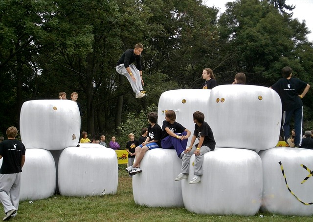 teenagers doing parkour across giant white cubes in a park as an alterantive to playing video games