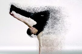 male dancer supporting himself on oone hand with the other one stretched out holding onto one of his legs. Half his body has faded away into little dts, making the image lok futuristic. Representing the future of fitness in the year 2020