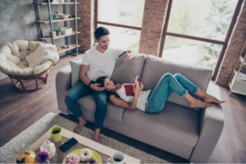 Young couple sat on a sofa enjoying their relaxing home haven