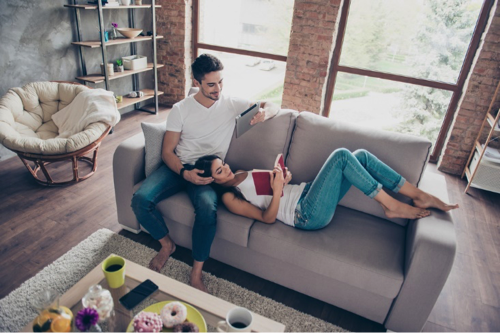 Young couple sat on a sofa enjoying their relaxing home haven