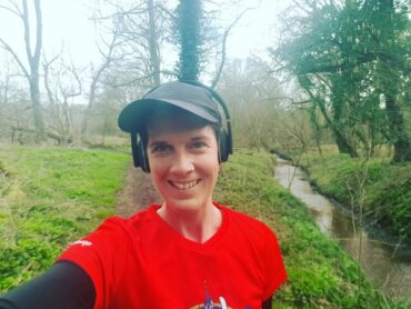 Becky Stafferton from chest up, takng a selfie of herself out running wiith headphones on listenong to music