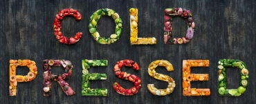 variety of fruts and vegetables laid out on a black background spelling out the words cold pressed