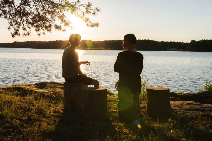 Two friends having a conversation by a river