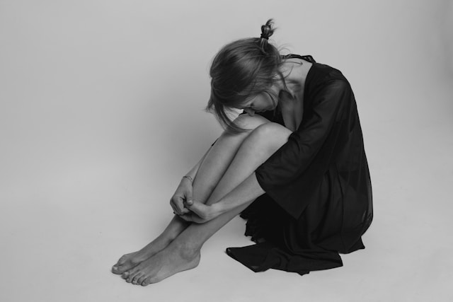 A woman sitting on the floor with her head on her knees