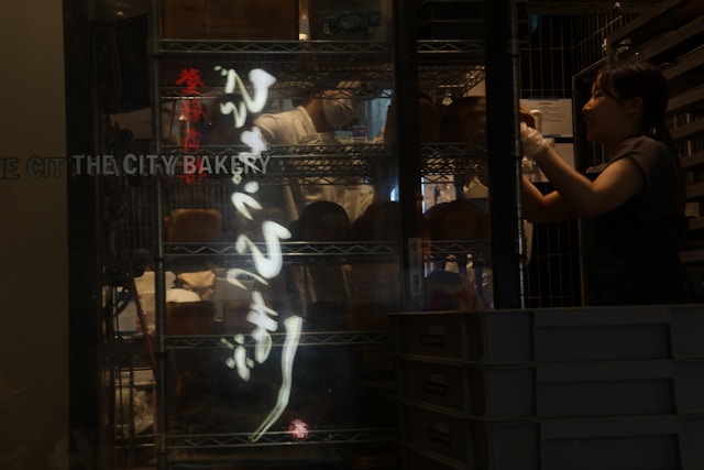 A shopper reaching into a glass door chiller cabinet in a small food shop