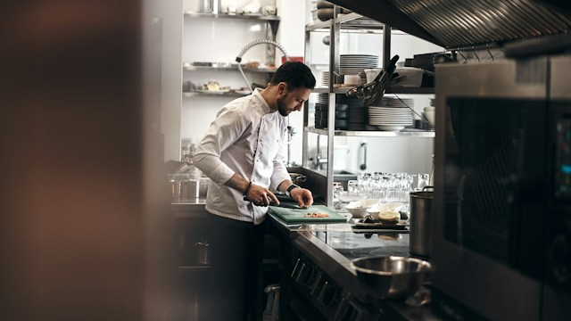 A chef plating food in a busy professional kitchen
